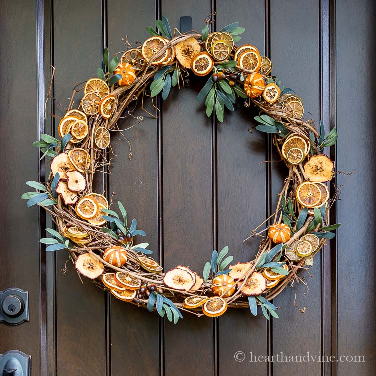 A grapevine wreath base with faux greenery and dried fruit slices glued all around.