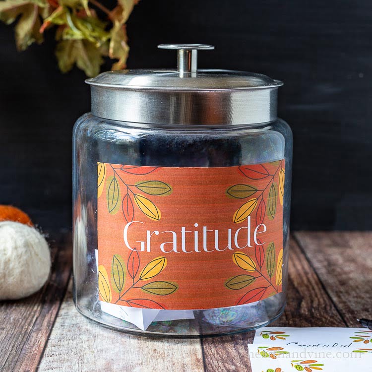 Gratitude jar on table next to a couple of pumpkins and write in cards.