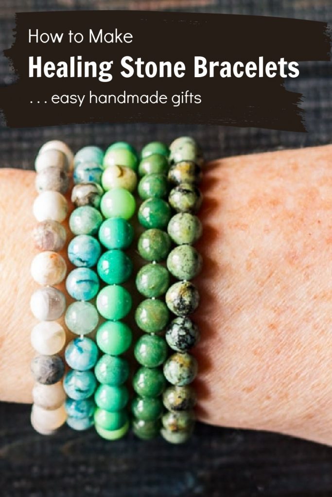 Five stone bracelets on a wrist in different colors.