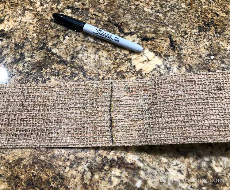 A black line down the center of a burlap ribbon and a black sharpie next to it.