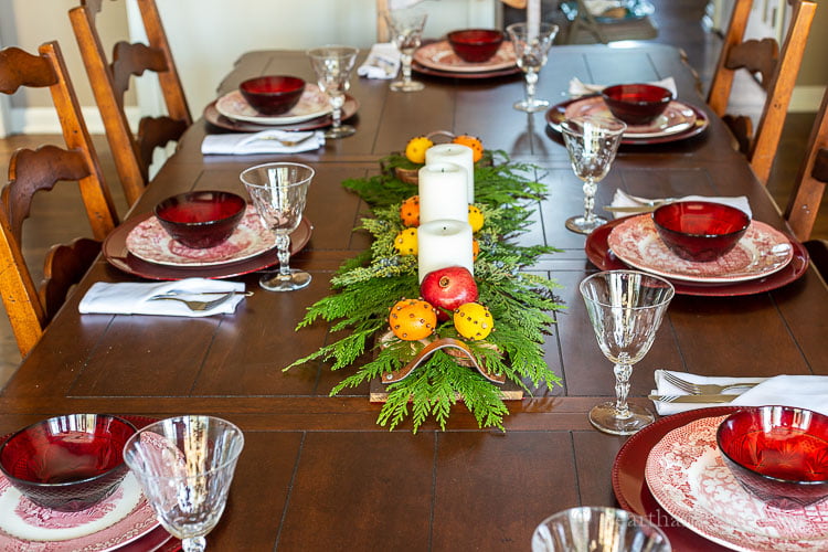Dining room tablescape set with red and white dishes and a DIY pallet centerpiece with cedar, white candles and clove studded citrus fruit.