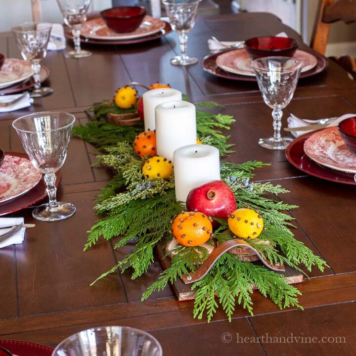 Pallet centerpiece with white candles, cedar branches, orange & lemons studded with cloves and pomegranates