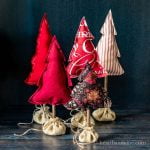 Five fabric Christmas trees stuffed in various colors and patterns of red.