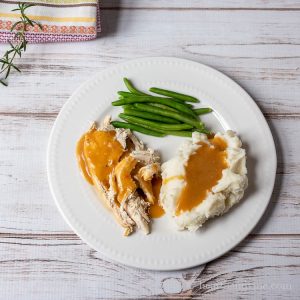 Plate with chicken and mashed potatoes with gravy and green beans on the side