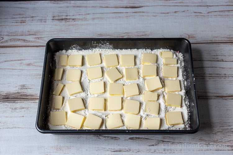 Cranberry dump cake before placing in the oven in a 9 x 13 inch baking pan with cake mix and slices of butter all over the top.