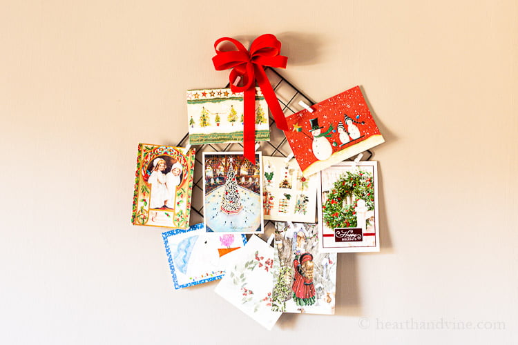 Christmas card hanging holder with red bow and mini clothespins fill with Christmas cards.