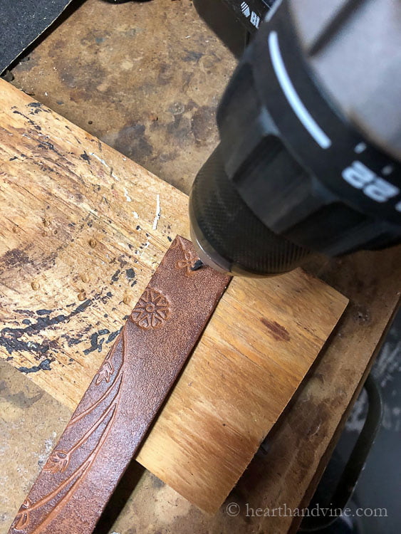 Drill making holes in the belt material.