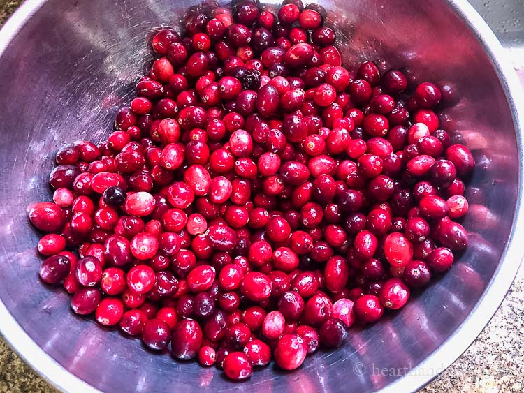 Fresh cranberries in a metal mixing bowl.