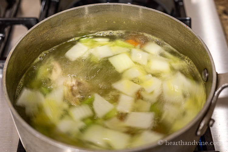 Homemade stock in a pot with onions, carrots, celery and chicken giblets/neck.