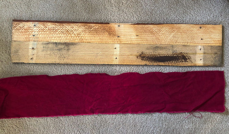 Backside of stained pallet boards next to a piece of flannel red fabric cut to fit the boards.
