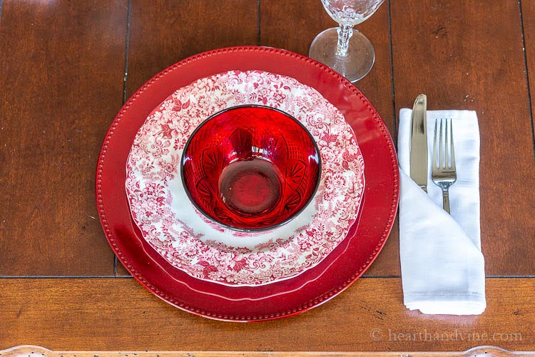 Red and white place setting with a folded napkin holding silverware.