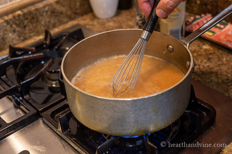 Whisking roux into pan dripping liquid and homemade stock to create a gravy.