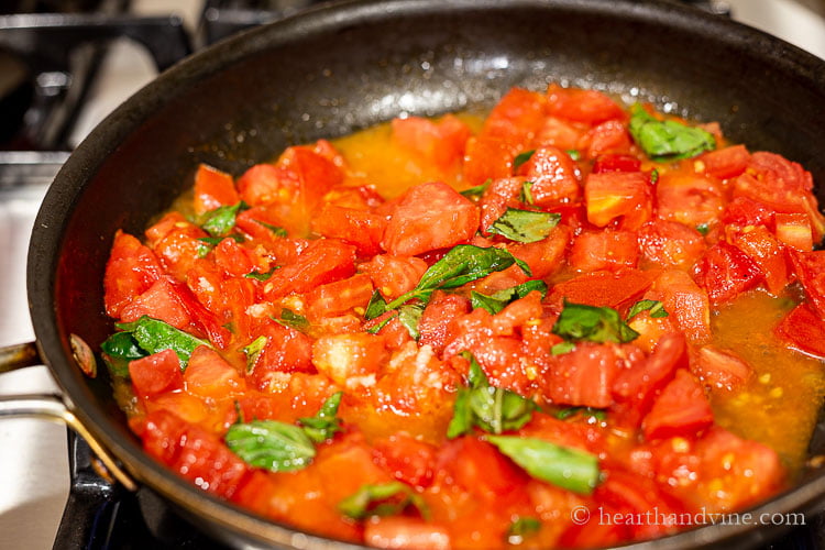 Chopped tomatoes, fresh basil cooking in a frying pan.