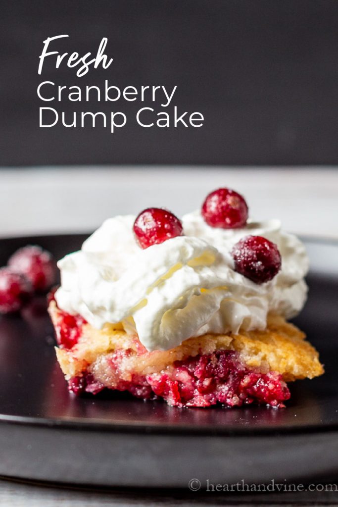 Serving of cranberry dump cake topped with whipped cream and sugared cranberries.