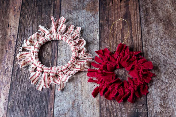 Two mini rag wreath ornaments. One is red and white striped and the other all dark red.