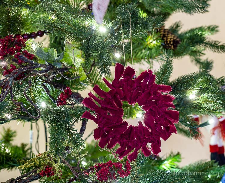 Dark red rag wreath ornament hanging on the tree.