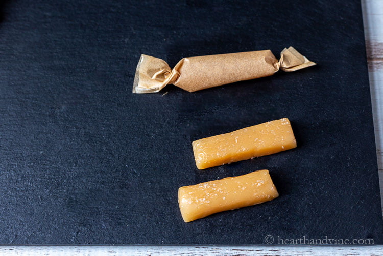 Homemade salted caramel candies. One wrapped in parchment and two unwrapped.