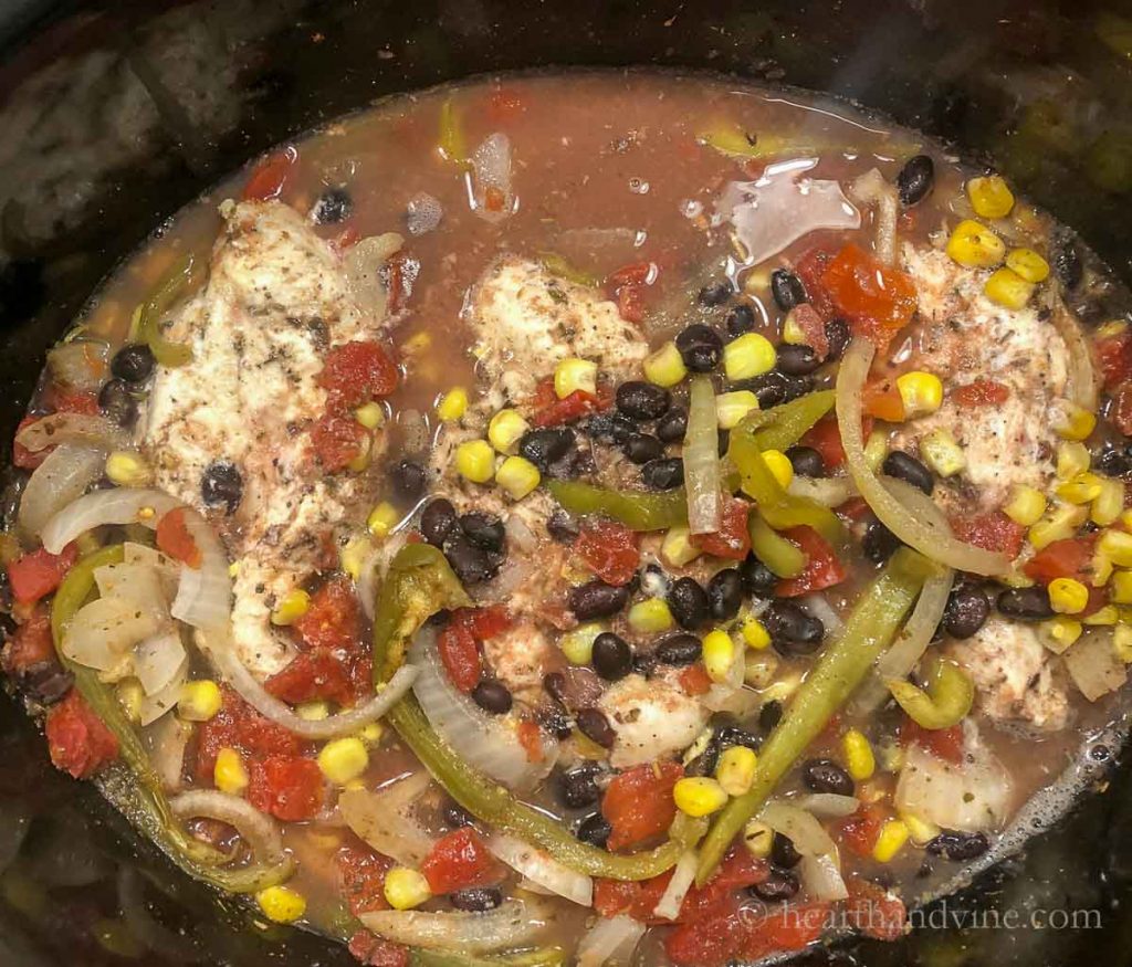 Boneless skinless chicken breast cooked with beans, corn, vegetables and spices in a slow cooker.