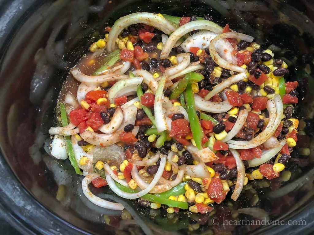 Slow cooker pot with beans, corn, peppers, onions and spices.