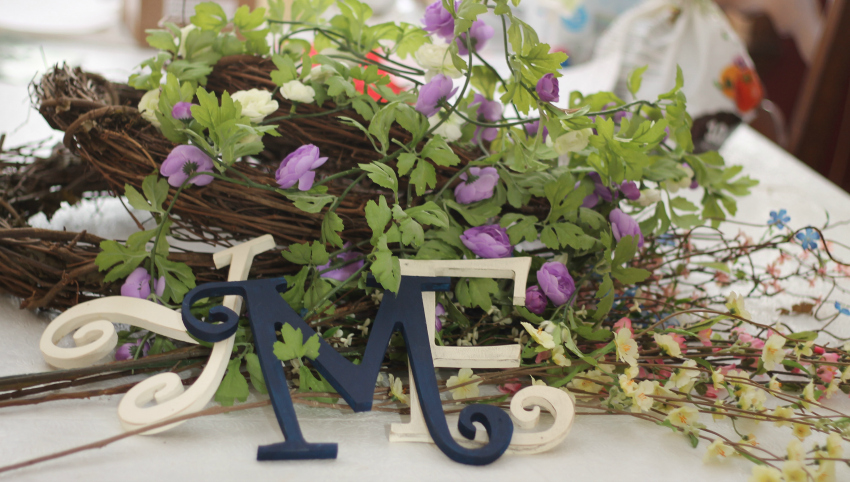 Piled up grapevine wreaths, artificial flowers and particle board letters in Y, M and E.
