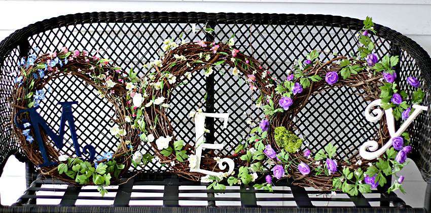 Three different spring wreaths on a black bench. 