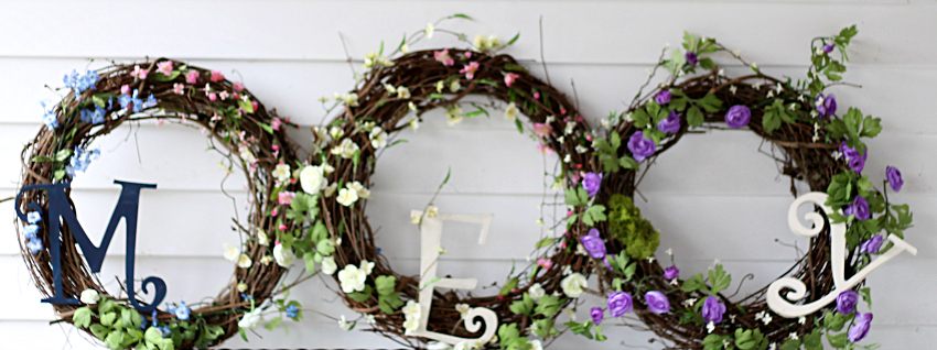 Three grapevine wreaths with spring blossoms and monogram letters.