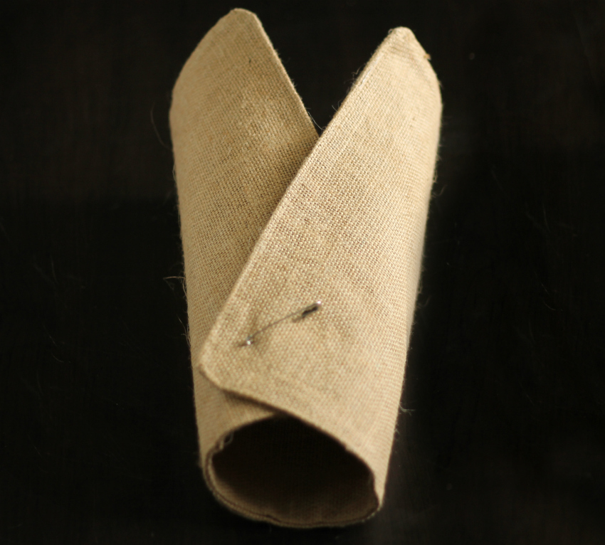 A safety pin holding the sides of a burlap placemat together.