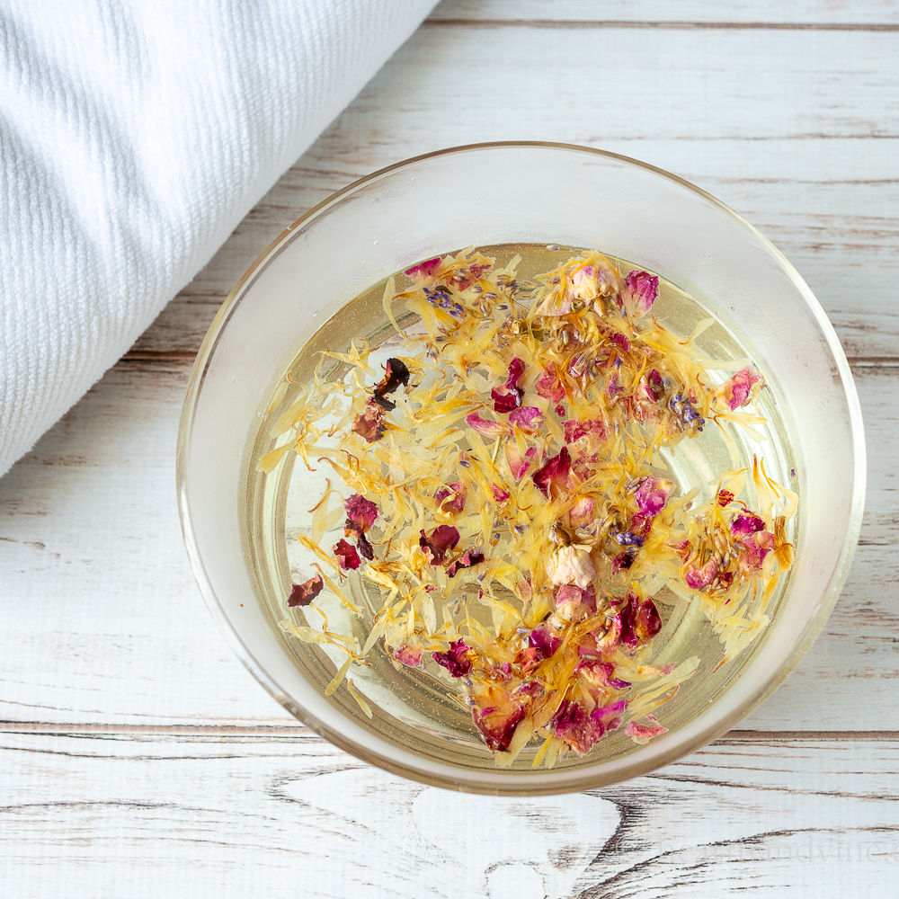Bowl of rose, calendula and lavender flower petals in hot water.