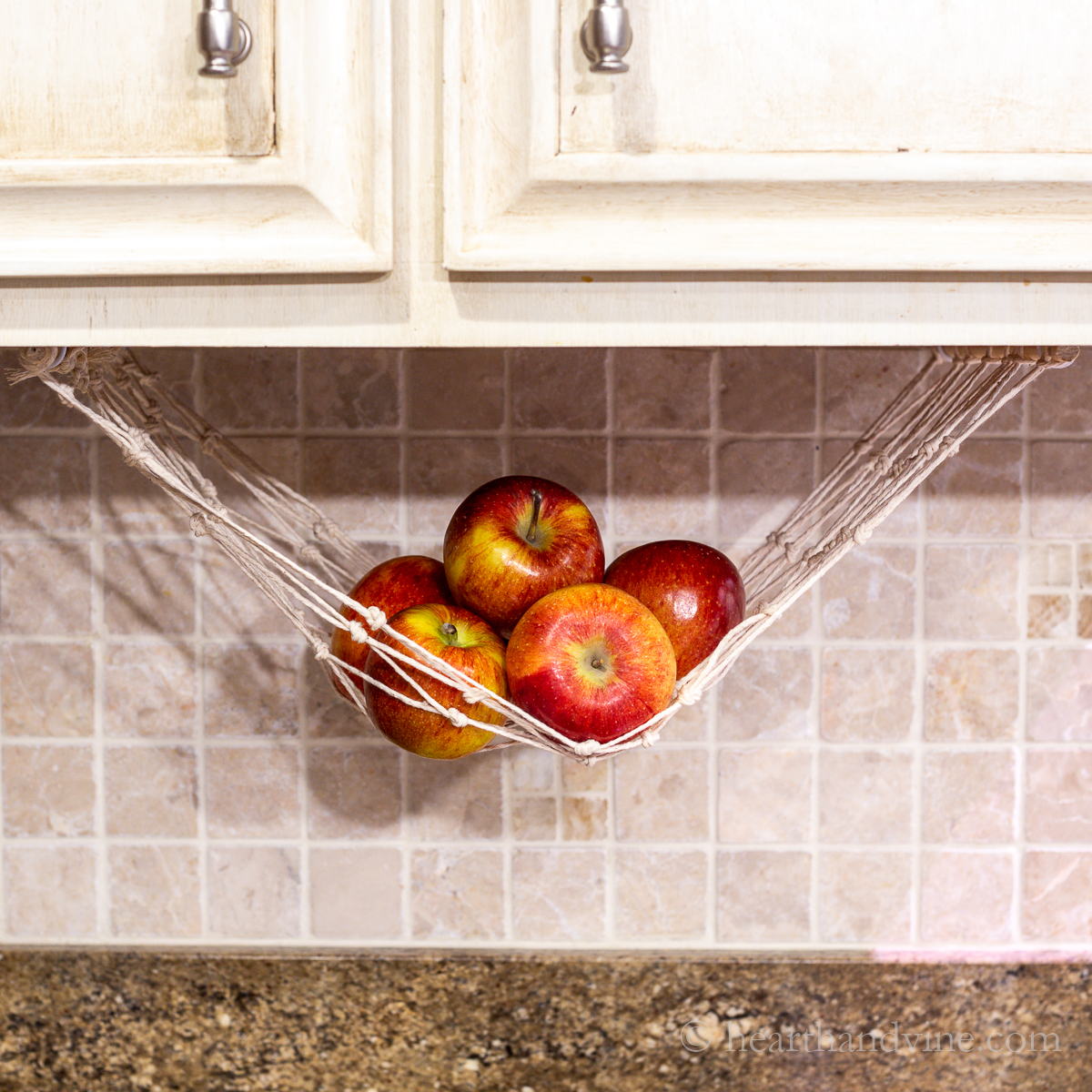 Apples in a macrame hammock under the cabinet
