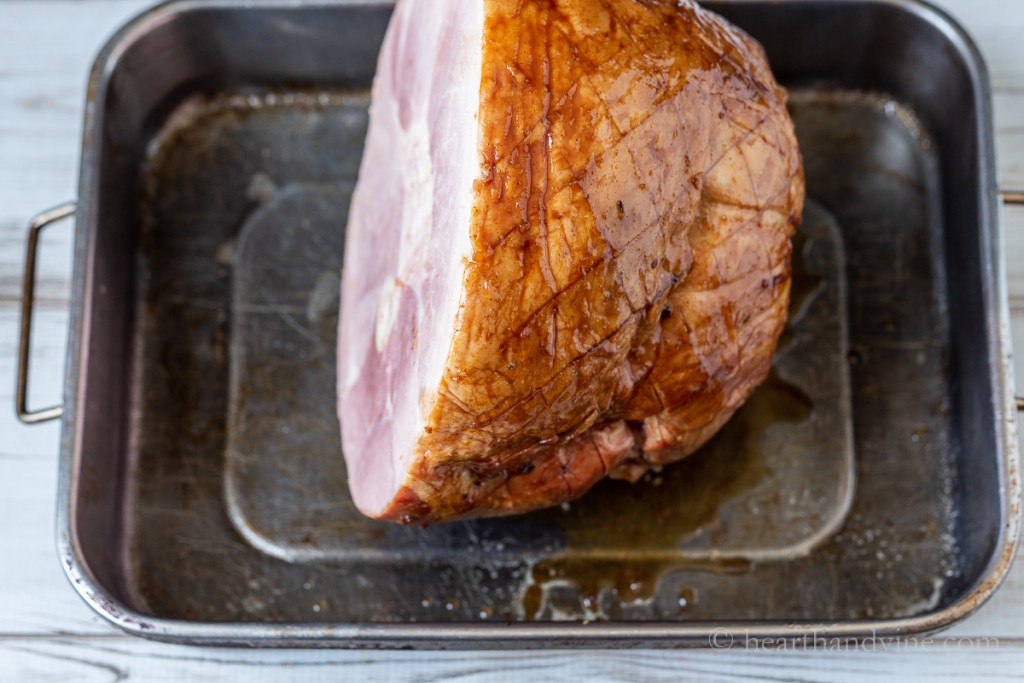 Scored ham with glaze in metal baking pan.