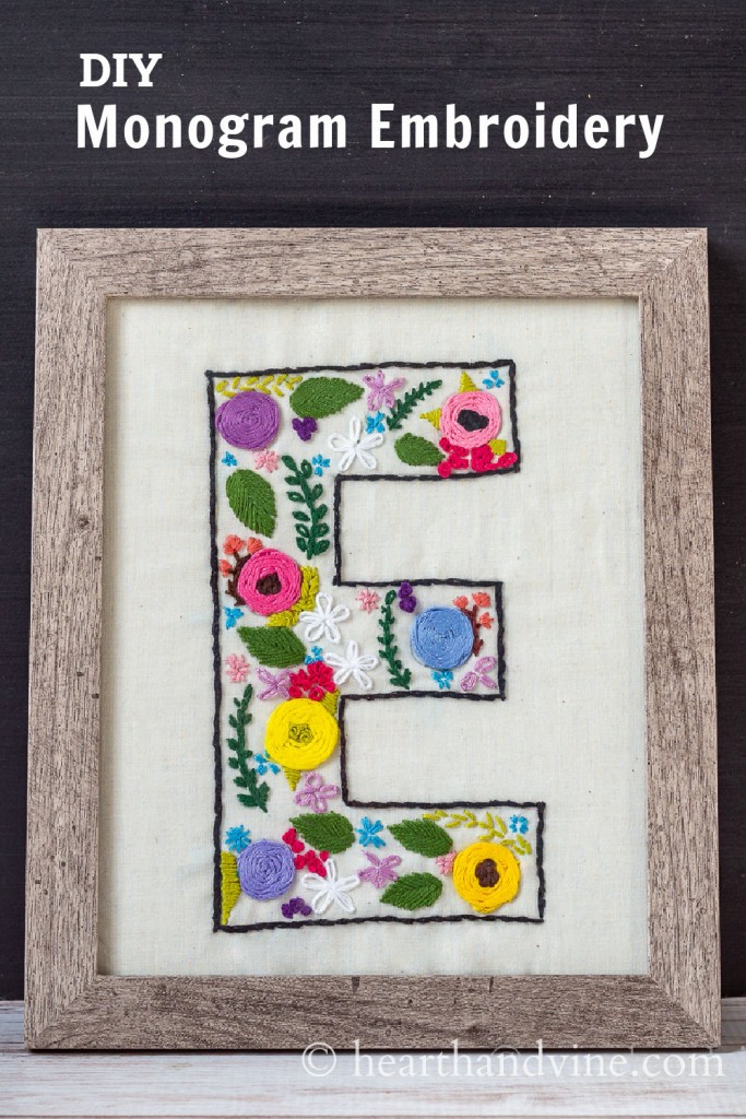 Floral embroidered monogrammed E pattern on muslin in a wood frame.