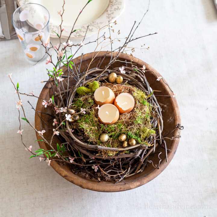 Round dough bowl with grapevines, moss, eggshell candles and spring blossoms.