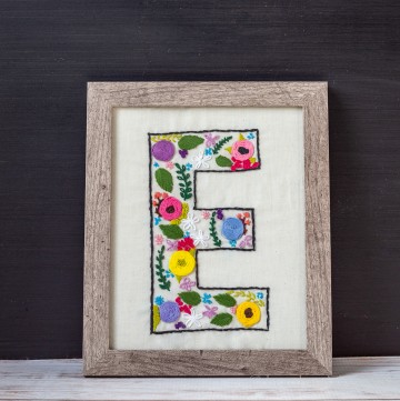 Framed letter E with embroidery flowers.