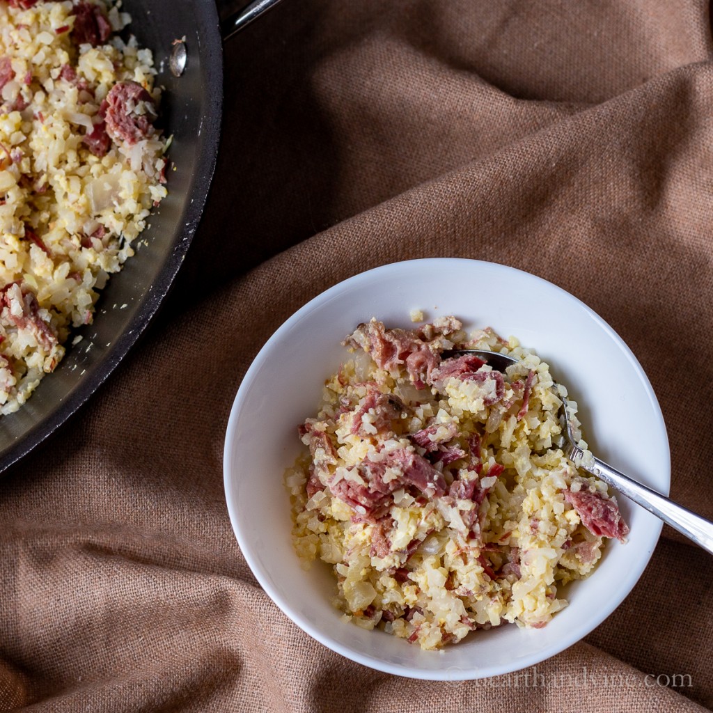 Bowl of low carb corned beef hash with eggs and cauliflower rice.