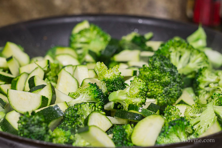 Broccoli, zucchini sautéing in a large skillet.