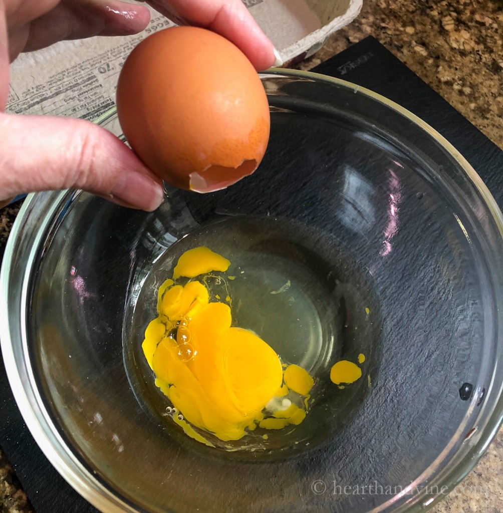 Pouring raw egg from shell into a bowl.