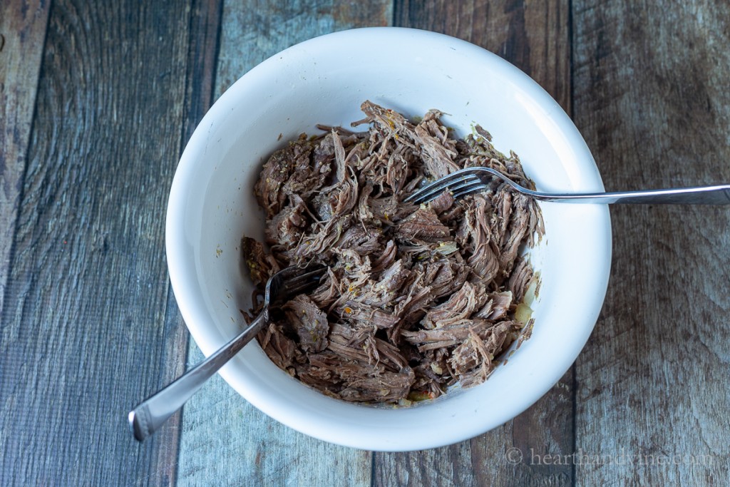 Shredded beef in a bowl with two forks.