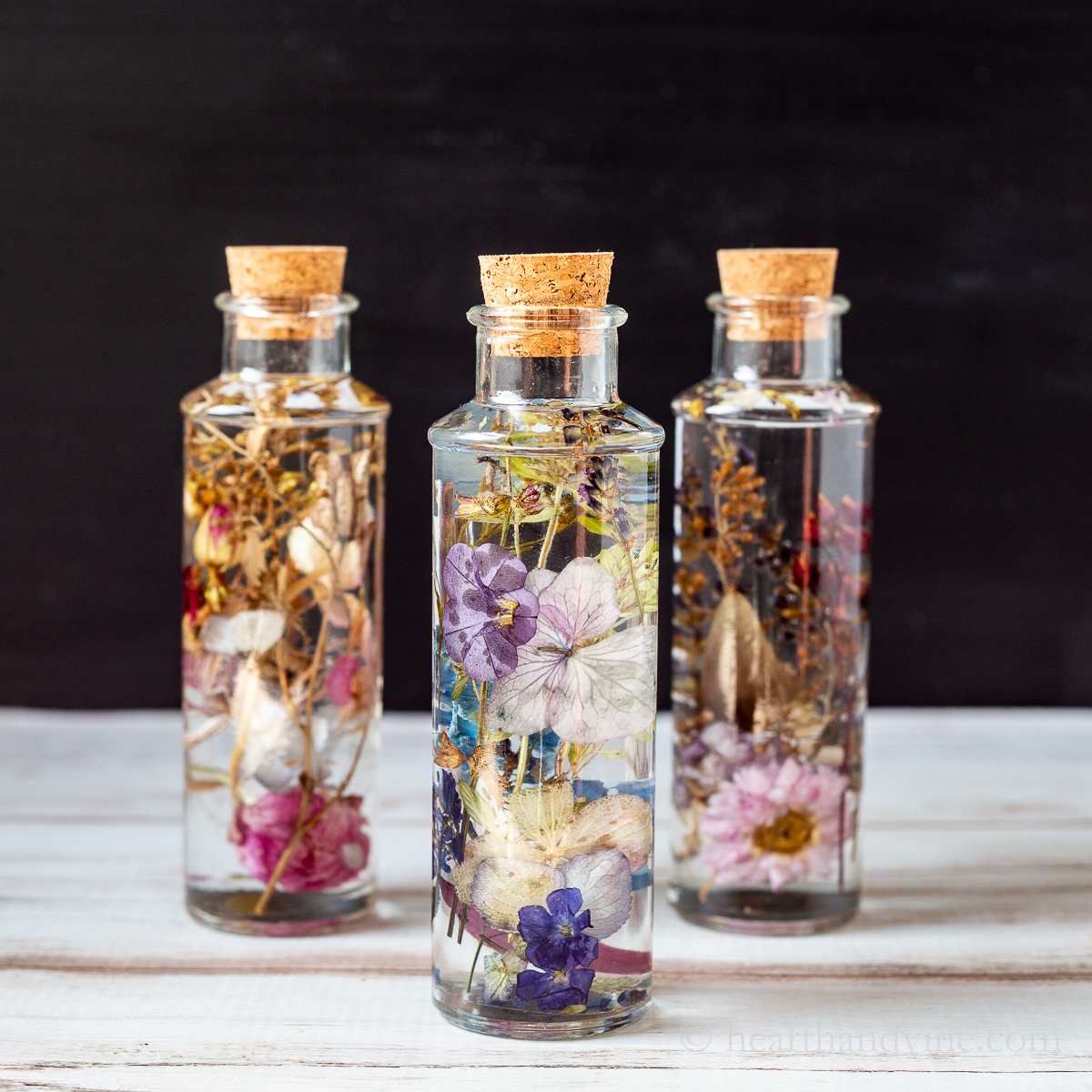 Three dried flowers in oil bottles
