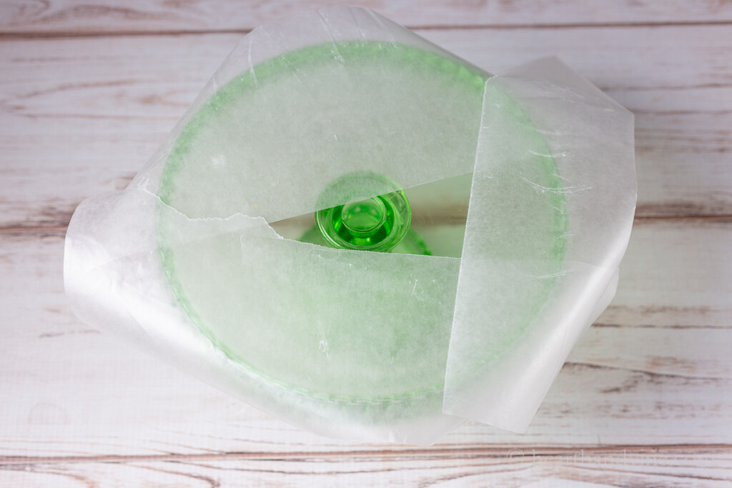 Green cake stand with three pieces of wax paper around the edge.