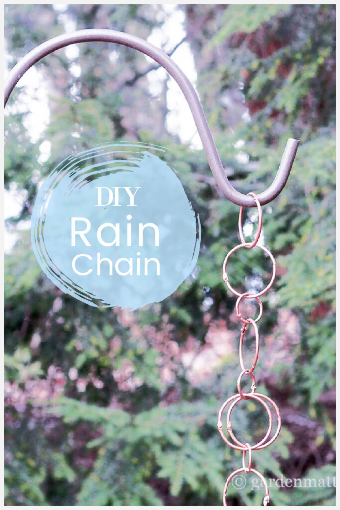 Copper looking rings form a rain chain hanging on a shepherd's hook in the garden.