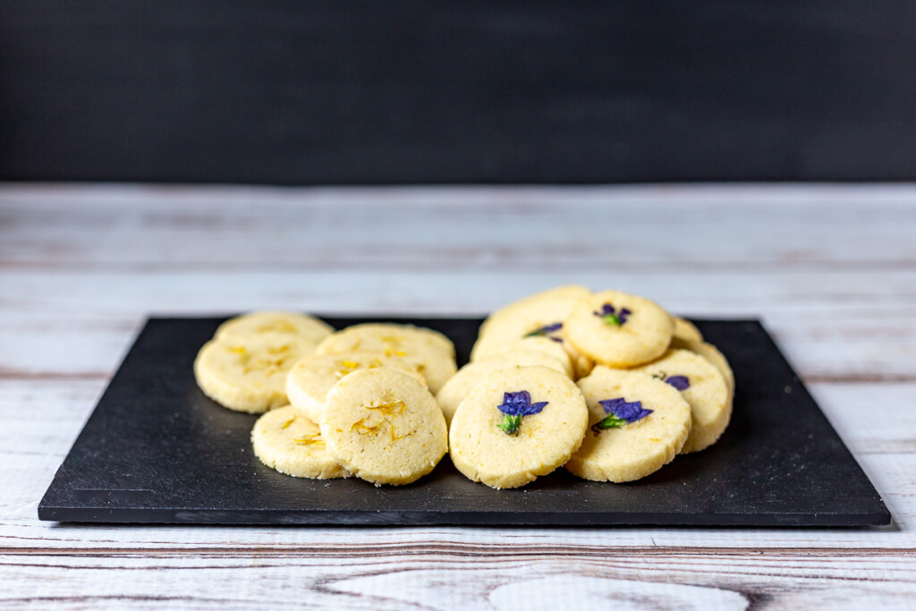 Black tray with dandelion and violet flower cookies.