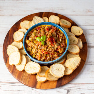 Roasted eggplant caponata on a plate with bread rounds