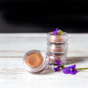 Violet lip balm in small round containers and a few live violet flowers