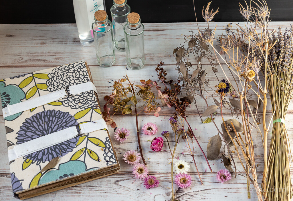 Flower press and dried flowers on table. Glass bottles with cork stoppers.