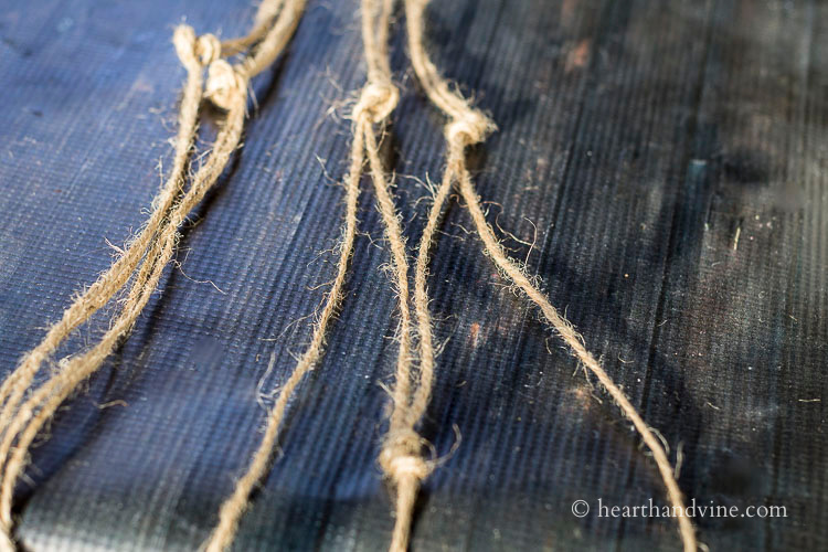 Twine pieces tied in knots by groups of two and then more knots below with adjacent twine pieces.