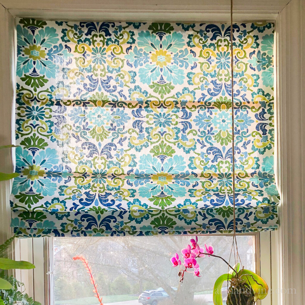 Blue and green Roman shades made from mini blinds hanging in a window.