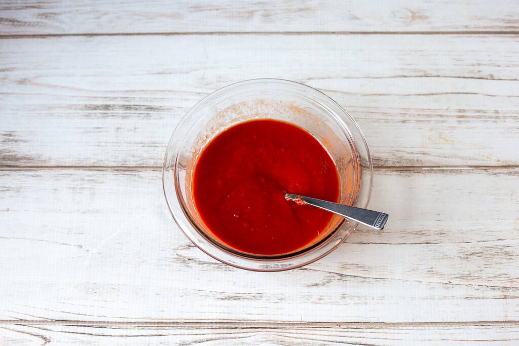 Bowl of thinned down tomato paste and a spoon.