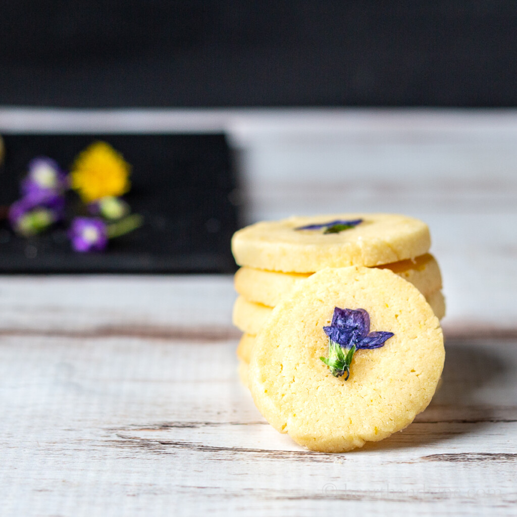Stack of edible flower cookies with dandelions and wild violet flowers.