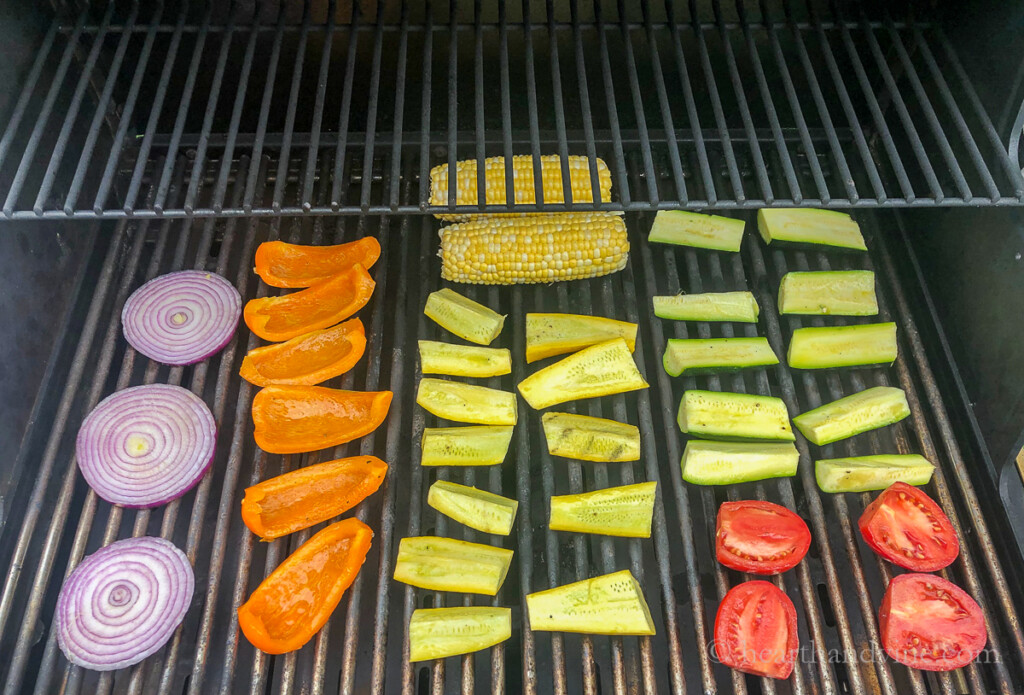 Red onion, sweet orange pepper, summer squash, corn on the cob, zucchini and plum tomatoes on the grill.