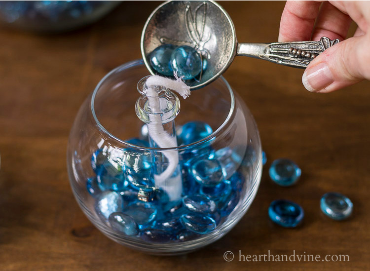 Filling the glass vase with blue dollar store gems.